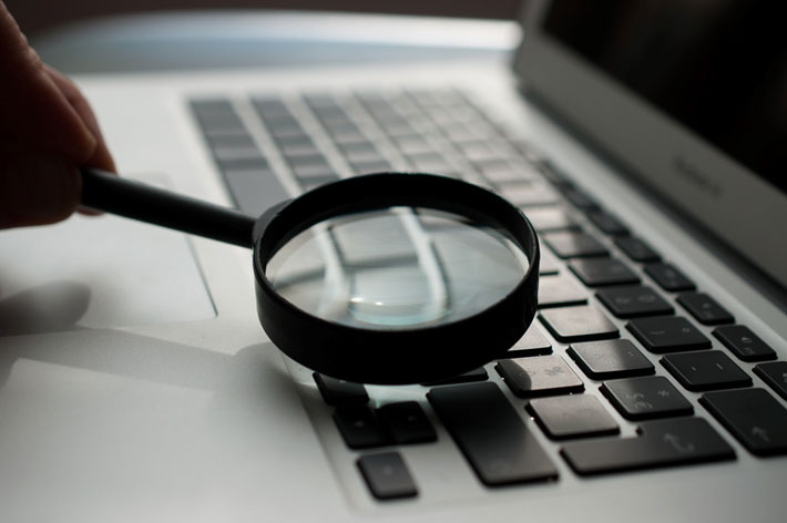 A magnifying glass held to a laptop keyboard