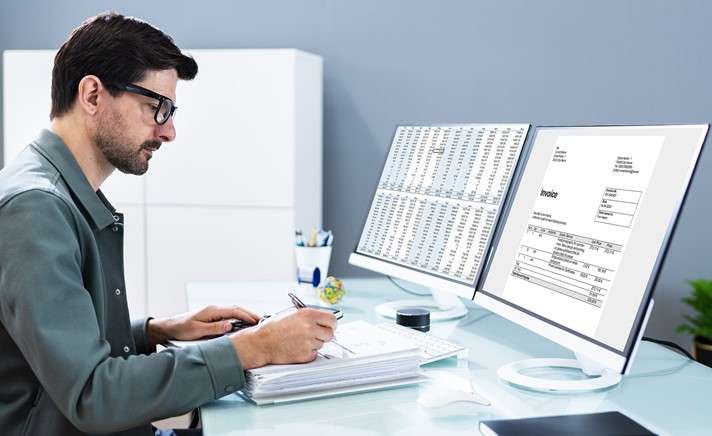 Accountant manually reviewing invoices without efficient bill scanning software