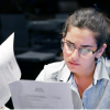 OCR vs AI OCR – woman looking through documents, sitting next to a computer