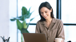 Woman smiling at desk working on computer, using automated invoice processing - Xtracta